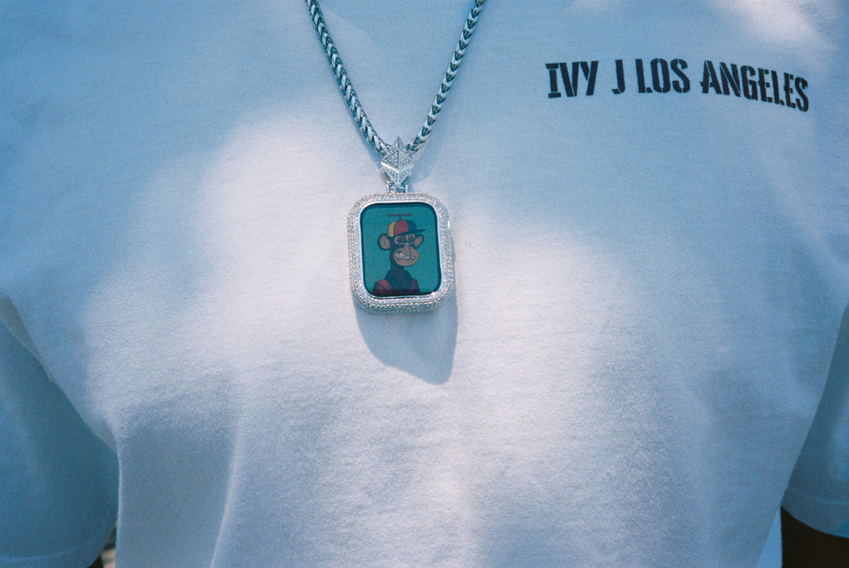 Custom Apple Watch jewelry, an iced pendant on a chain, worn on a white Ivy J Los Angeles t-shirt
