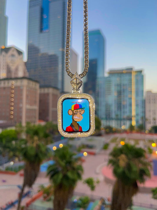 Custom iced Apple Watch pendant in 14k gold hanging in front of downtown Los Angeles buildings