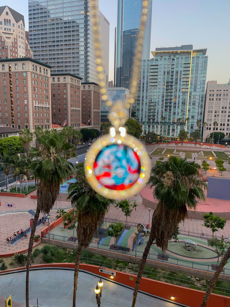 Glowing iced Pixel Watch necklace pendant above Los Angeles palm trees and city buildings