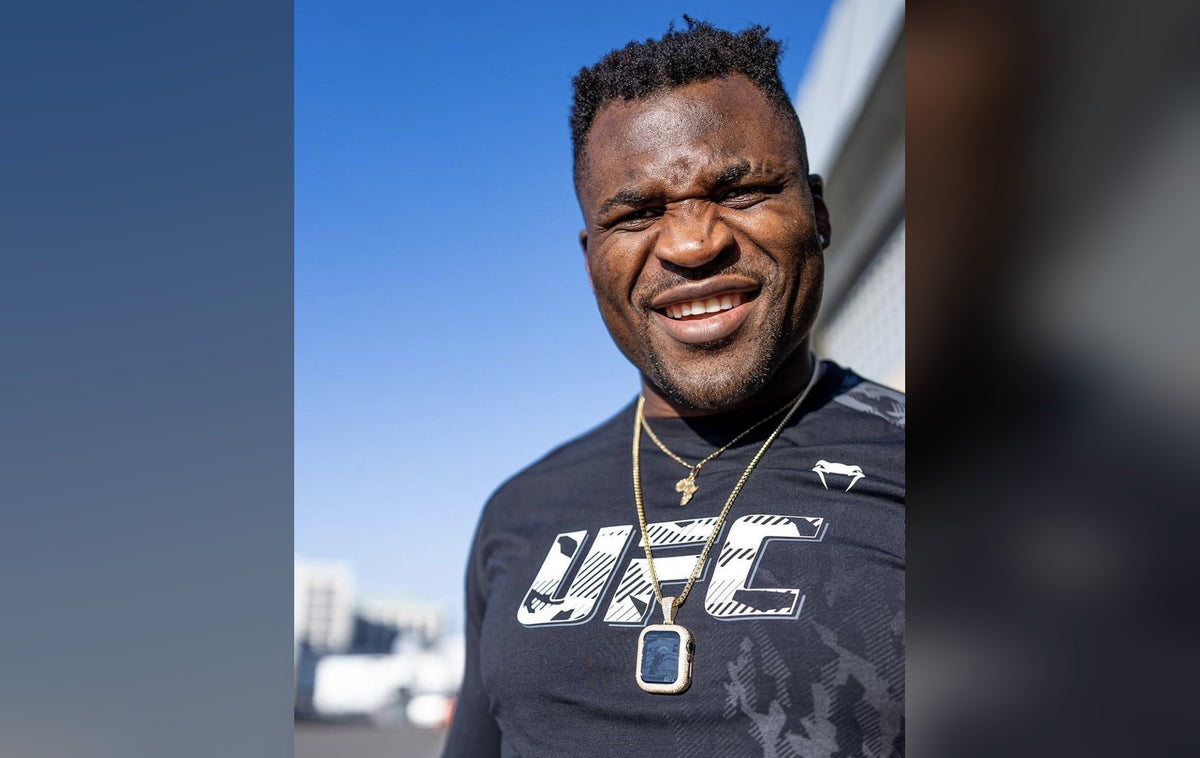 Francis Ngannou smiling in a UFC shirt wearing a gold Ivy J Apple Necklace
